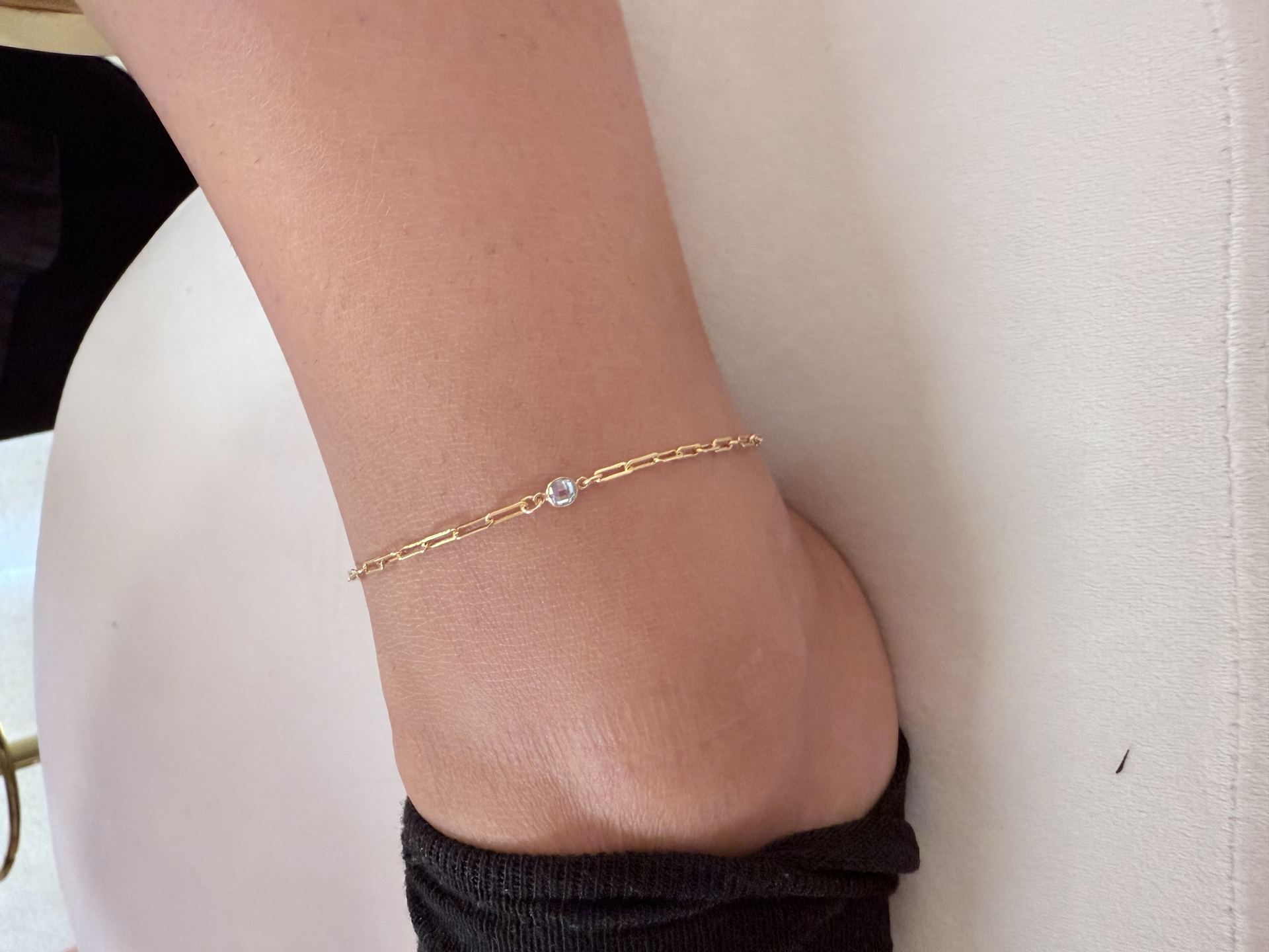 Gold paperclip-link bracelet with a single round clear gemstone charm