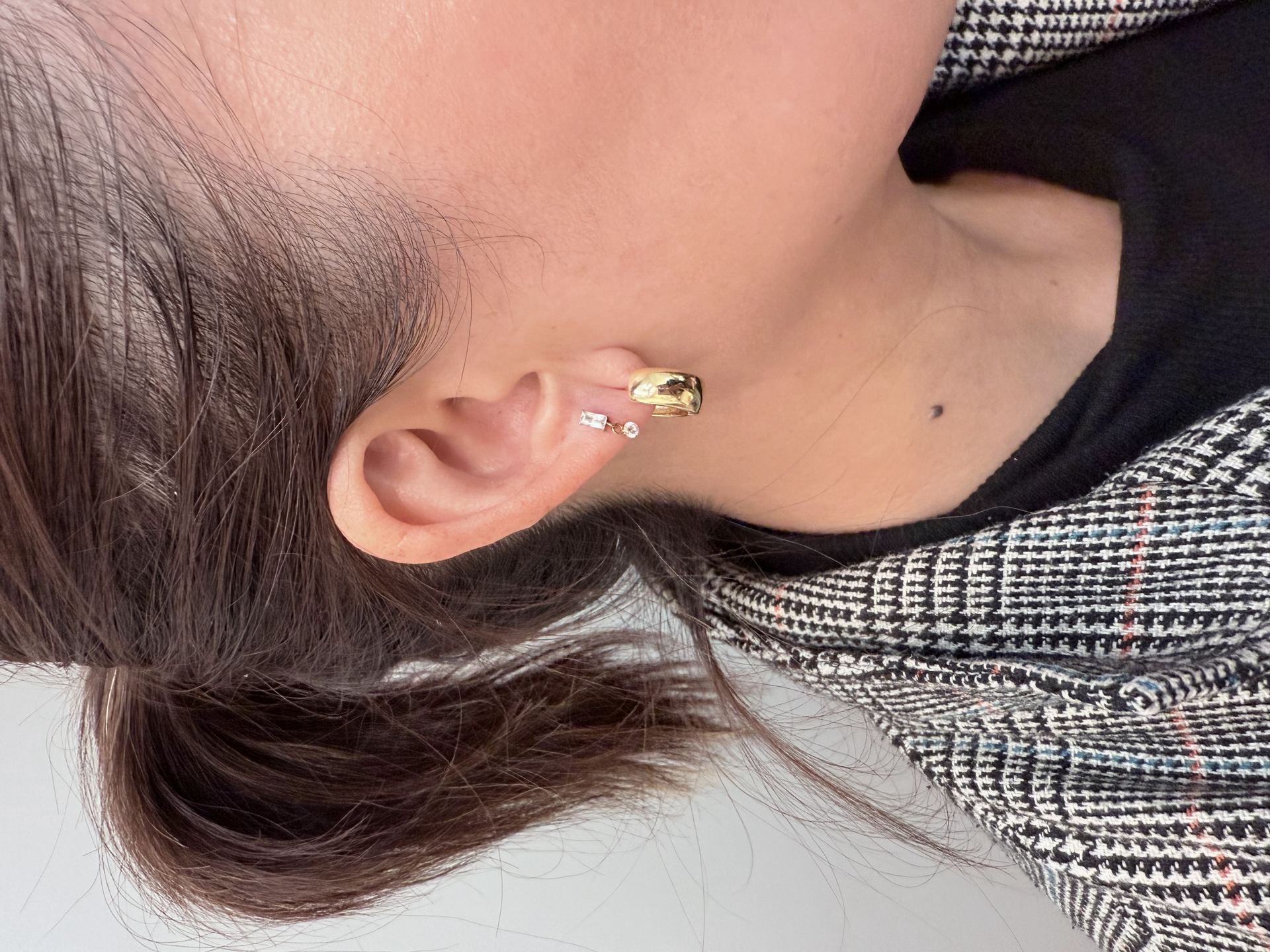 Gold ear cuff with a baguette gemstone and a dangling round clear gemstone charm